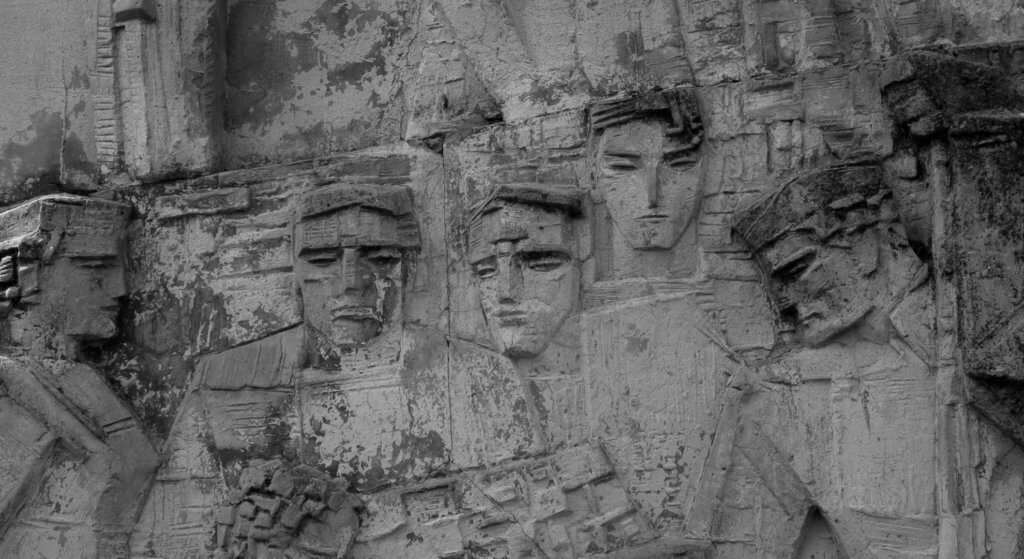Close up of a monument or sculpture, showing faces carved in stone.