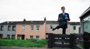 Jacob Rees Mogg stepping over a fence in a