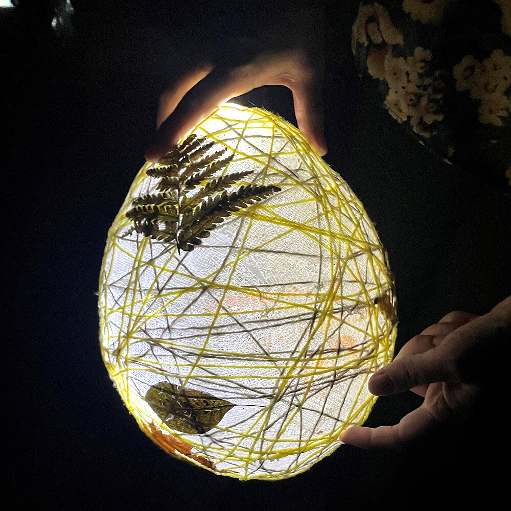 A picture of a lantern made with paper, wire, and leaves.